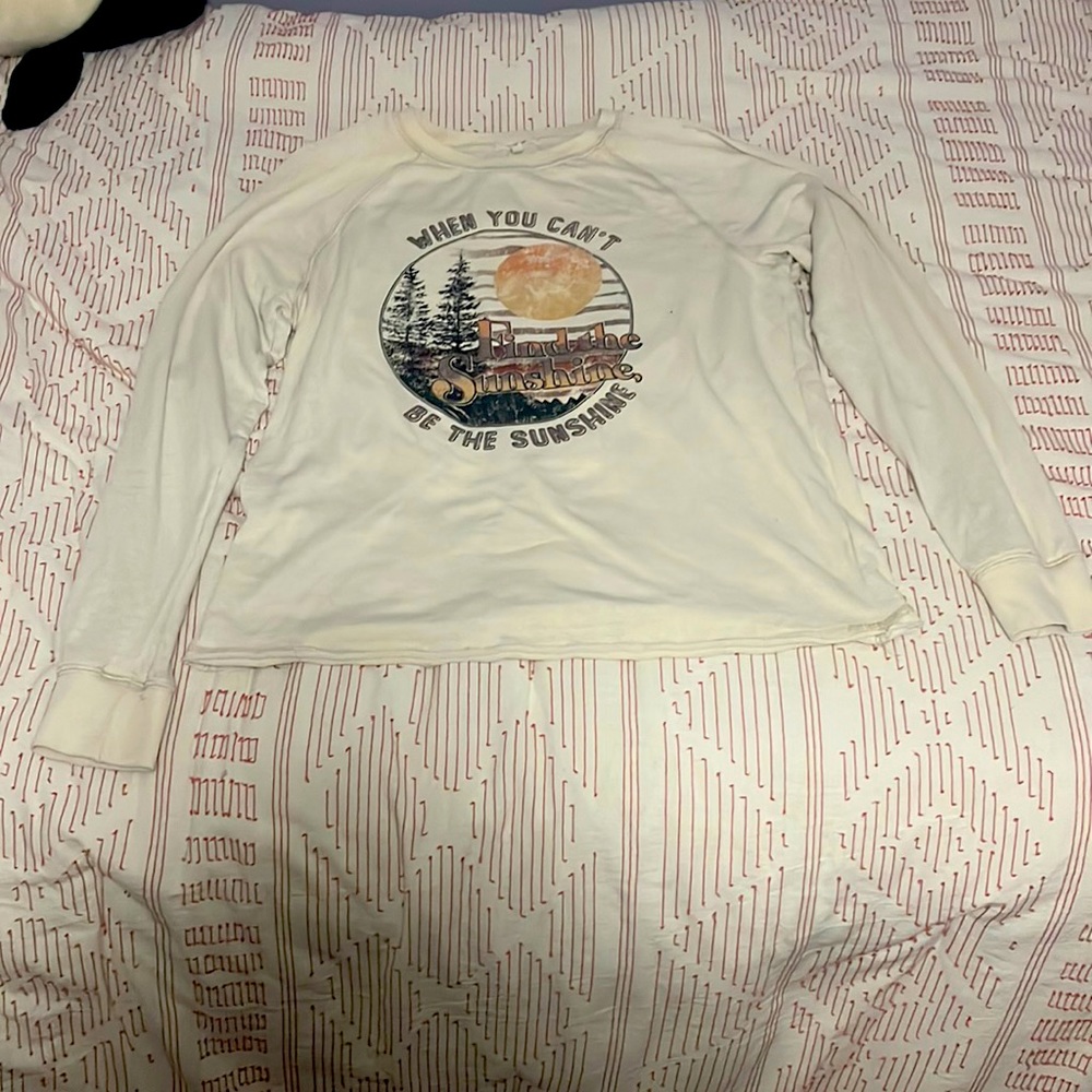 Front of the shirt says “when you can’t find the sunshine, be the sunshine”